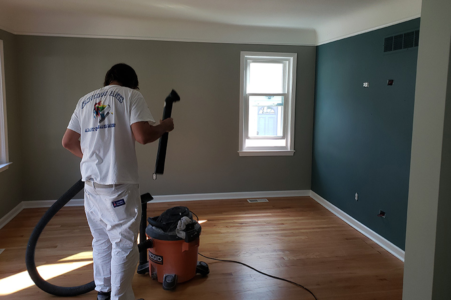 man-with-vacuum-in-room-with-gray-and-teal-walls